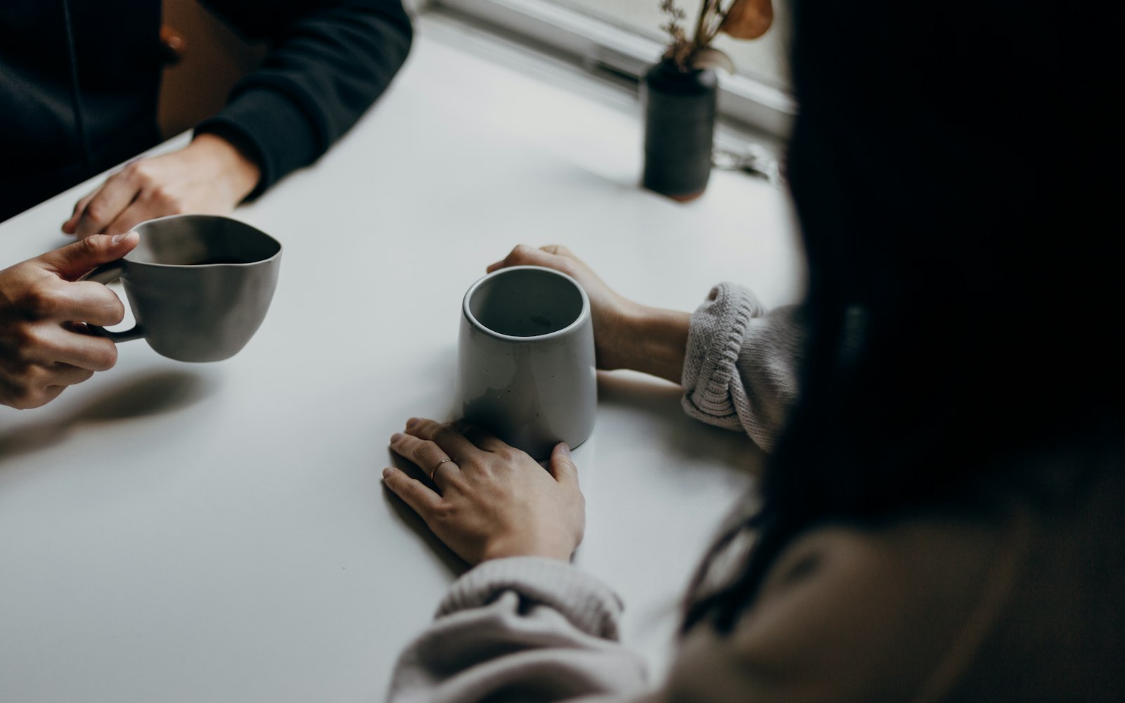 Dos personas conversando con una taza de café sobre la mesa