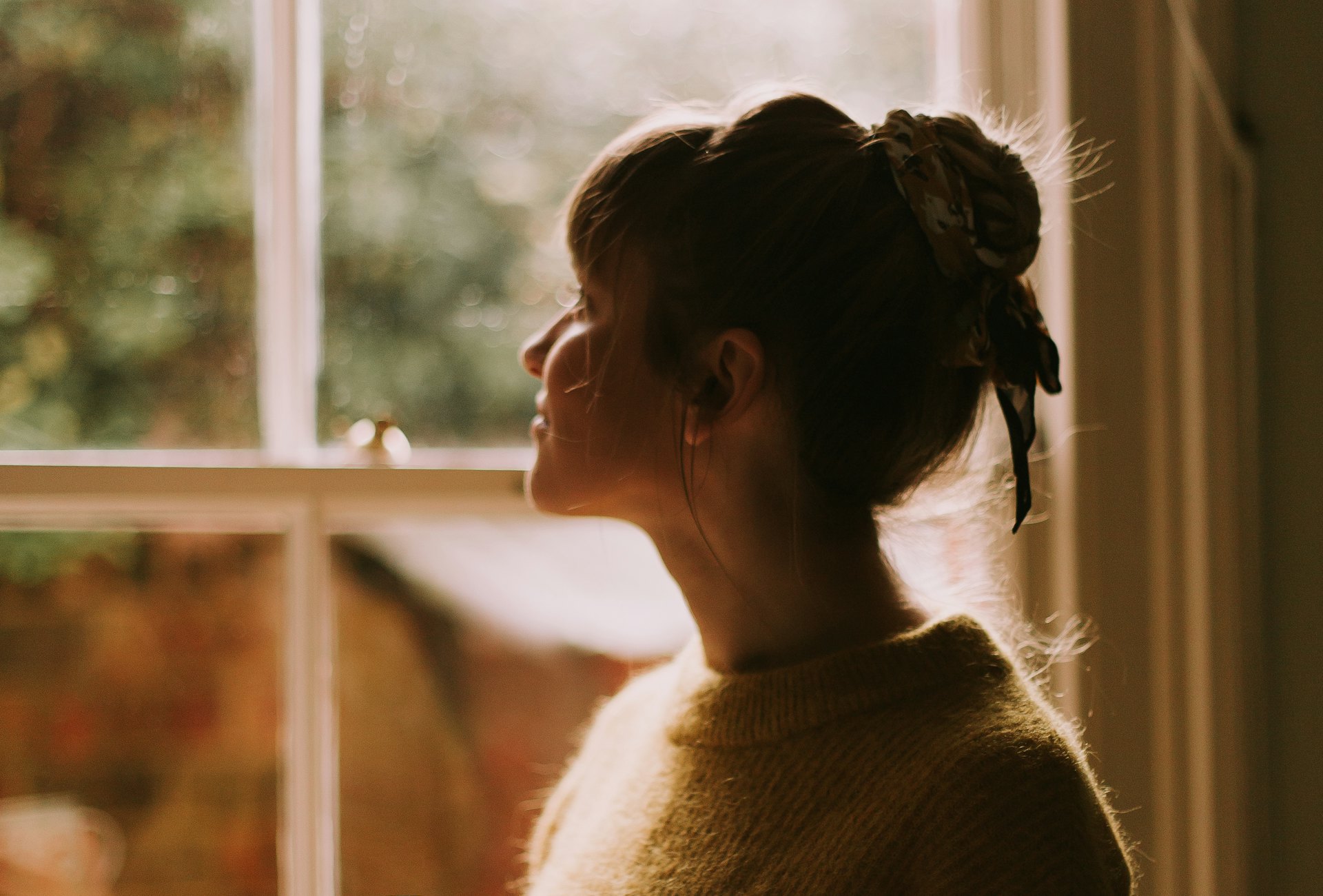 Mujer tranquila junto a una ventana con luz cálida