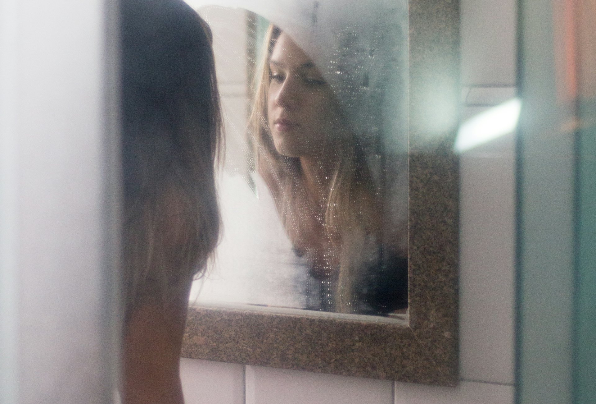 Mujer reflejada en un espejo empañado con luz suave