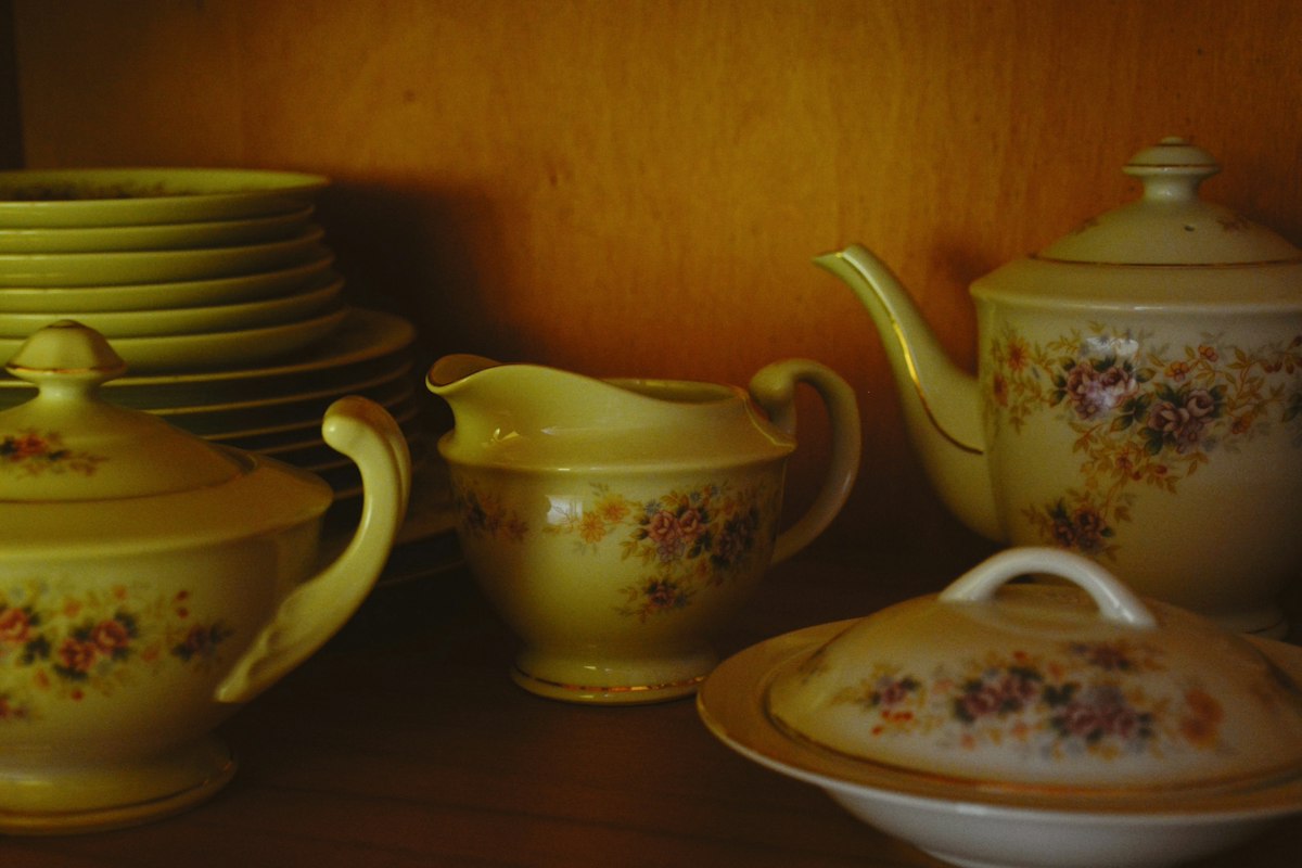 Juego de té de loza con flores pintadas, guardado en un mueble de madera