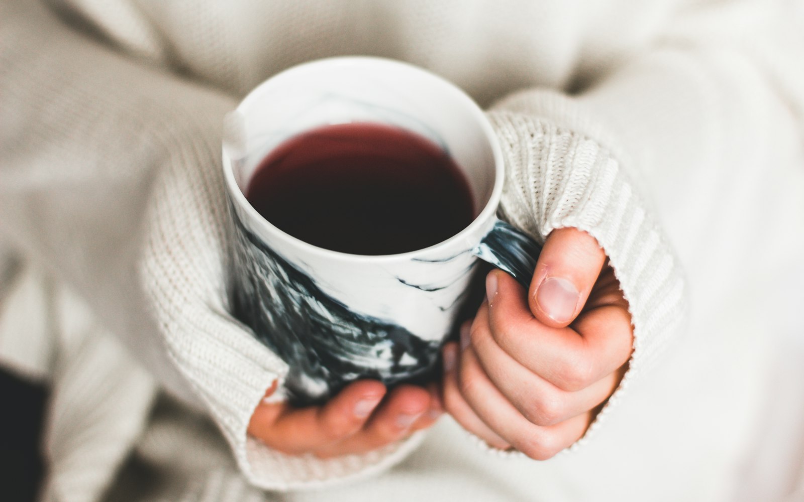 Manos abrigadas sosteniendo una taza caliente